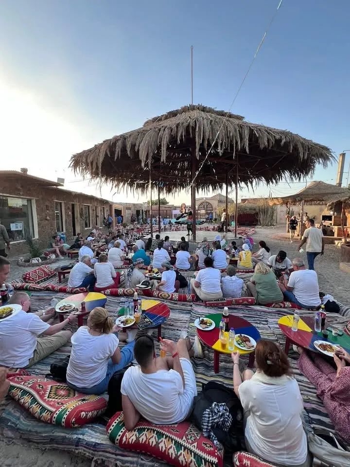 Guests sharing dinner beneath a shaded desert pavilion