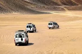 Safari vehicles travelling across an open desert plain