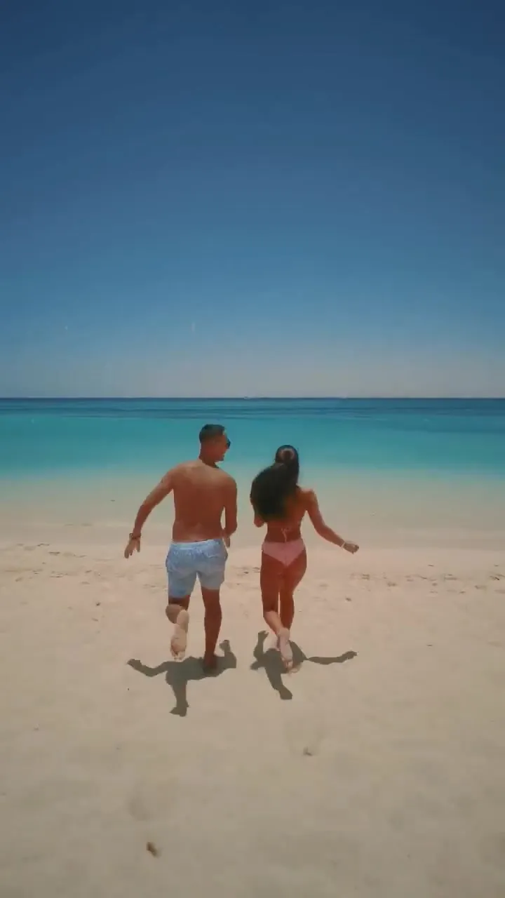 A couple walking from the white sand into the clear water at Hula Hula Beach