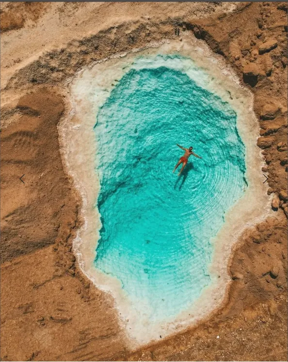 Traveller floating in a small turquoise Siwa salt pool