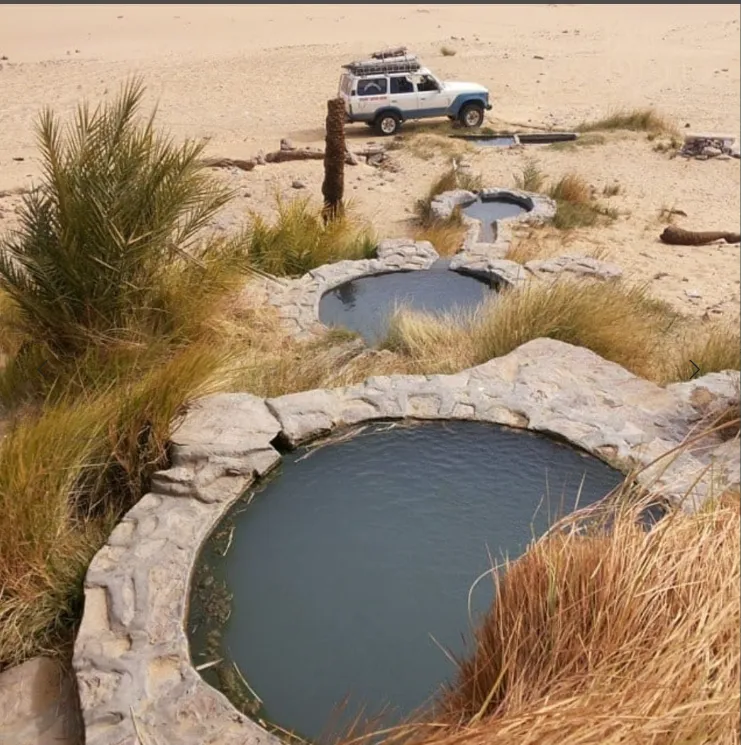 Natural spring pools beside a desert safari vehicle in Siwa