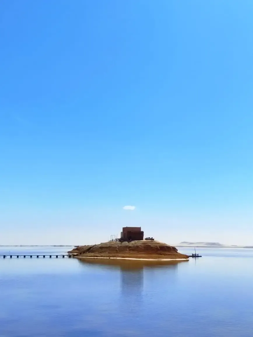 Small island reflected in the calm water of Siwa Oasis