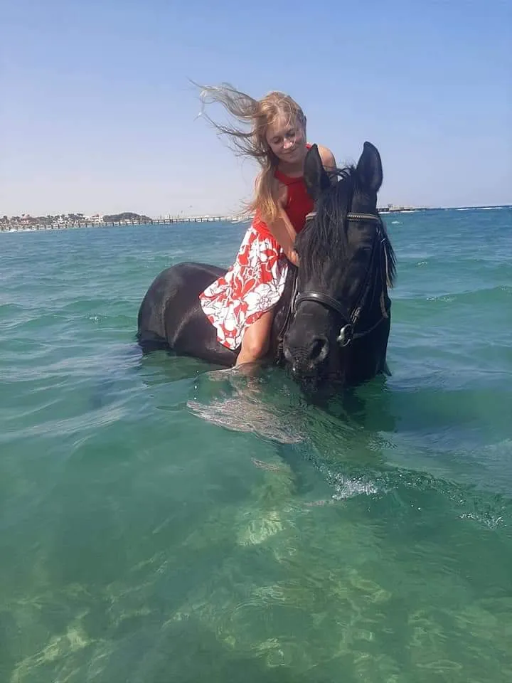 Guest swimming with a horse in the turquoise sea